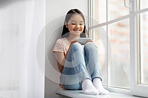 Joyful korean girl schooler playing games on cellphone, panorama