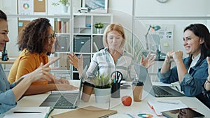 Joyful ladies multi-ethnic team talking and doing high-five enjoying professional achievement