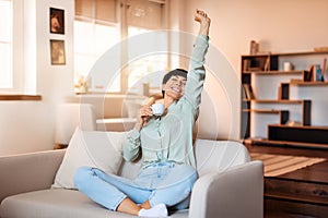 Joyful lady in modern living room enjoying break and coffee