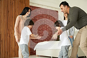 Joyful latin children, little twin boys smiling while having fun with their sister and parents indoors. Mom and dad