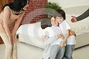 Joyful latin children, teenage girl and two little twin boys hugging each other while having fun indoors. Mom and dad