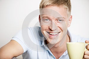 Joyful laughing young man enjoying a cup of coffee.