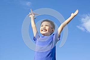 Joyful little boy holding a toy with blue sky