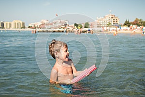 Joyful little boy shoots from a water-pistol at someone in the sea