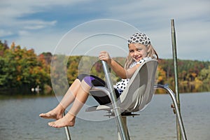 joyful little girl sitting and relaxing above the water in the life guard chair