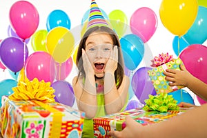 Joyful little kid girl receiving gifts at birthday