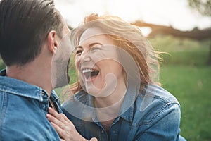 Joyful loving couple having rest on meadow