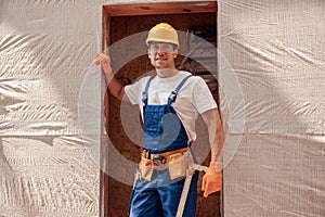 Joyful male builder standing in doorway at construction site