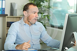 joyful male businessman looking with awe at computer screen