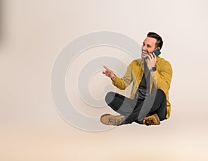 Joyful male professional communicating with business associates over smart phone. Handsome businessman laughing happily and