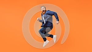 Joyful man with beard jumps and shouting in excitement, studio