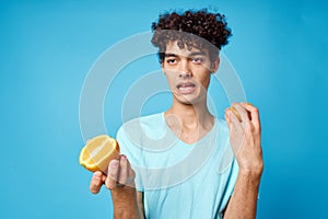 joyful man in blue t-shirt with oranges in hands studio isolated background