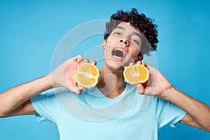 joyful man in blue t-shirt with oranges in hands studio isolated background