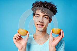 joyful man in blue t-shirt with oranges in hands studio isolated background