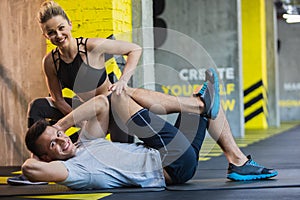 Joyful man is exercising with female coach indoors