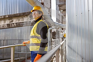 Cheerful male engineer standing near metal pipe at factory