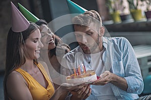 Joyful man holding his birthday cake at the party