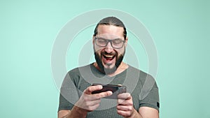 Joyful man laughing while playing a game on his smartphone