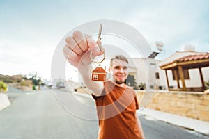 Joyful man shows keys on the background of new home