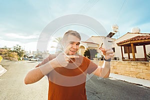 Joyful man shows keys on the background of new home