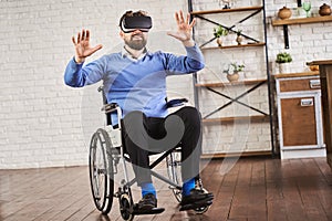 Joyful man sitting on a wheelchair and wearing a VR headset