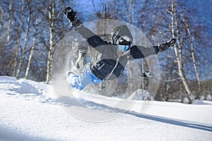 Joyful man skier in a mask jumps into the loose snow and rejoices in winter