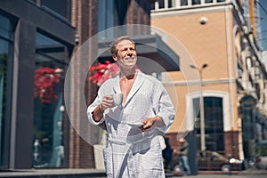 Joyful man in white bathrobe walking on the street