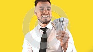 Joyful Man in a White Shirt Counts Cash on a Yellow Background. Positive Emotions from Money, Happiness from Salary