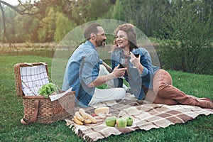 Joyful man and woman drinking wine near river