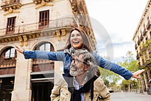 Joyful mature couple having fun together enjoying vacation on city street