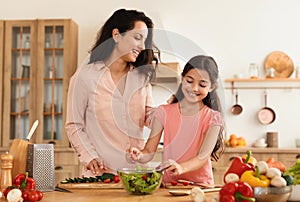 Joyful Middle Eastern Mother And Daughter Cooking Salad At Kitchen