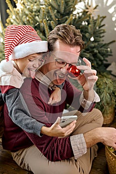 Joyful millennial father having fun laughing with adorable little kid son,taking photo