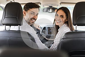 Joyful millennial spouses enjoying travel by car together