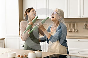 Joyful mom and excited adult daughter having fun in kitchen