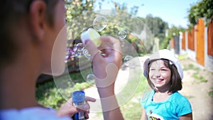 Joyful Moments: Boy Blowing Bubbles as Girl Gleefully Catches Them in the Sunlight