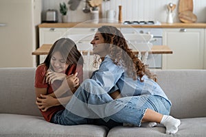 Joyful mother and daughter having fun and laughing while spending time together at home
