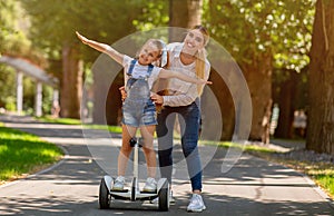 Joyful Mother And Daughter Riding Segway Having Fun Outside