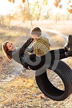 A joyful mother swings with her little son on a wheel