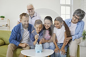 Joyful multi-generational family teaches little boy to collect money in piggy bank.