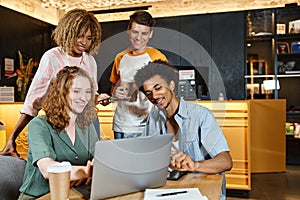 joyful multiethnic buddies looking at laptop