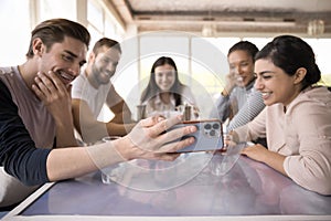 Joyful multiethnic teammates gathering at table in cafe