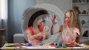 Joyful multiracial kids smudging hands with paints children art club happiness