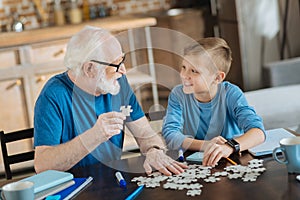 Joyful nice man collecting jigsaw puzzles