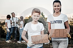 Joyful nice woman holding a volunteer sign