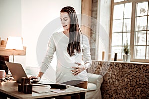 Joyful nice woman standing in front of her laptop