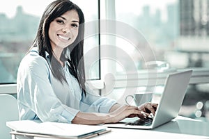 Joyful occupied woman sitting and working with her laptop.