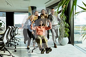Joyful Office Colleagues Engage in a Playful Chair Race on a Sunny Afternoon