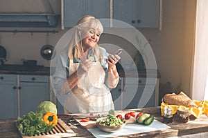 Joyful old woman choosing song on smartphone