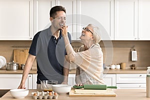Joyful older mom and son baking together, cooking breakfast