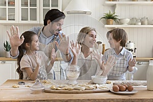 Joyful parents and two happy kids in aprons baking together